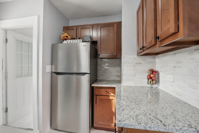 kitchen with light stone countertops, stainless steel fridge, and decorative backsplash