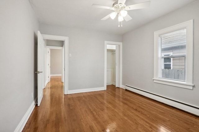 unfurnished bedroom featuring hardwood / wood-style flooring, ceiling fan, baseboard heating, and a closet