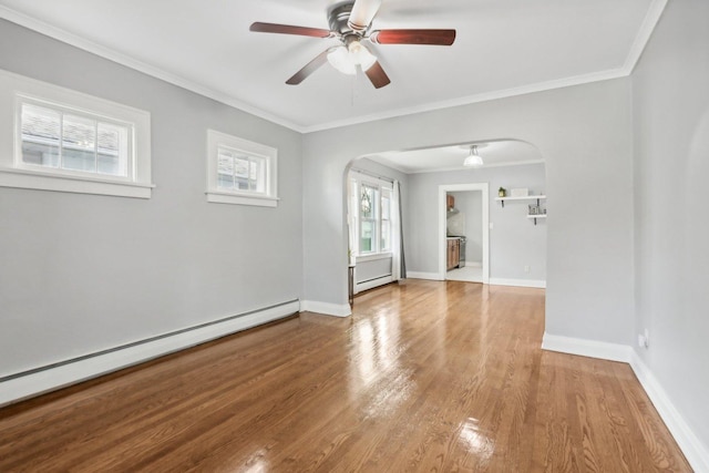 spare room with baseboard heating, ornamental molding, and hardwood / wood-style floors