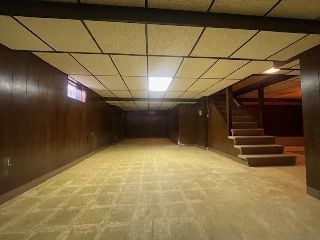 basement with a paneled ceiling and wooden walls