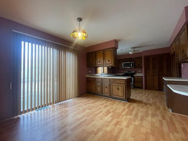 kitchen featuring pendant lighting, light hardwood / wood-style flooring, stainless steel appliances, and kitchen peninsula