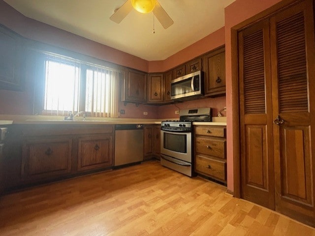 kitchen with ceiling fan, stainless steel appliances, sink, and light wood-type flooring