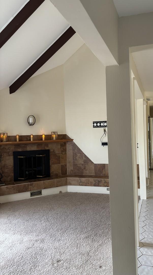 unfurnished living room featuring lofted ceiling with beams and carpet flooring