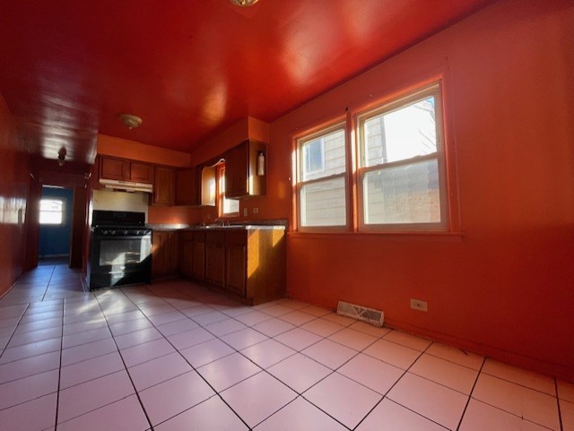 kitchen with sink, range, kitchen peninsula, and light tile patterned floors