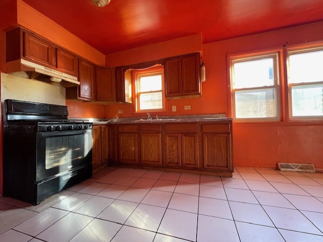 kitchen featuring black gas range oven, sink, and light tile patterned floors