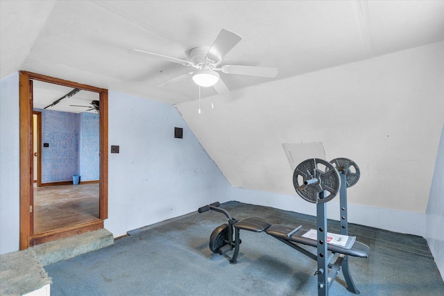 exercise room featuring ceiling fan, vaulted ceiling, and dark colored carpet