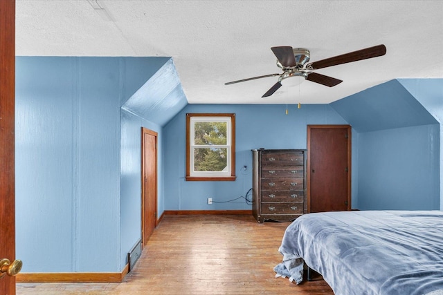 bedroom featuring lofted ceiling, ceiling fan, a textured ceiling, and light wood-type flooring