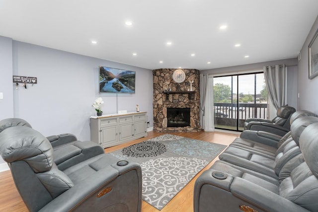 living room with a stone fireplace and light wood-type flooring