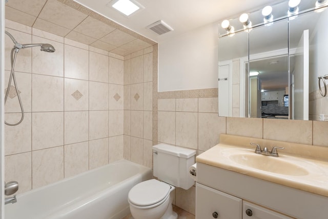 full bathroom featuring tile walls, vanity, tiled shower / bath, and toilet