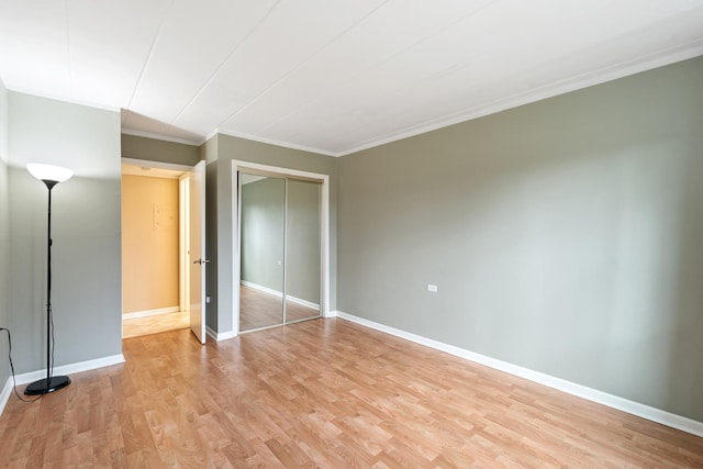 unfurnished bedroom featuring ornamental molding, light hardwood / wood-style floors, and a closet