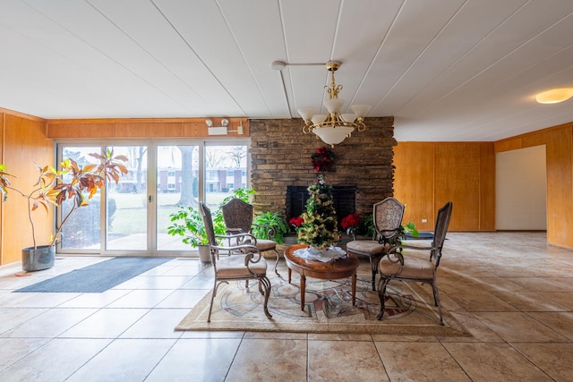 tiled dining room with wooden walls, a chandelier, and a fireplace