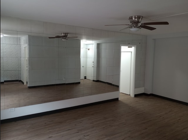 unfurnished room featuring tile walls, dark hardwood / wood-style floors, and ceiling fan