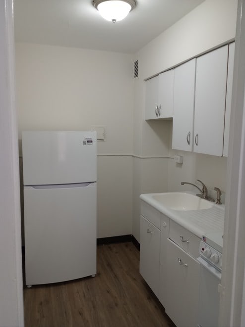 kitchen with sink, dark wood-type flooring, white cabinets, and white refrigerator