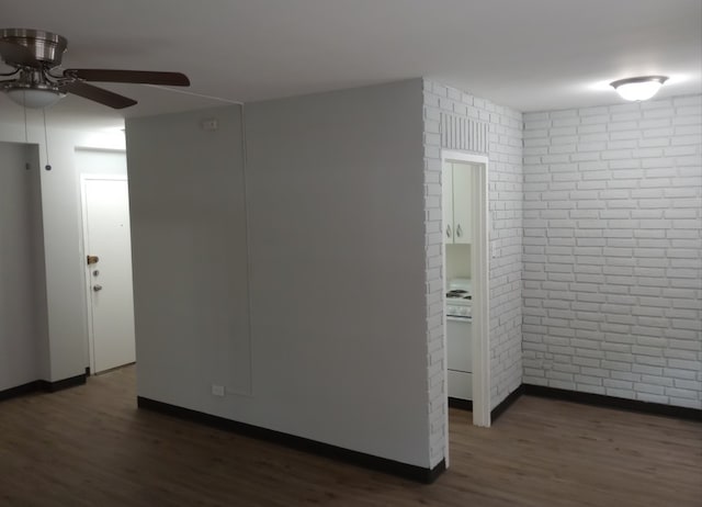 unfurnished room featuring ceiling fan, brick wall, and dark hardwood / wood-style flooring