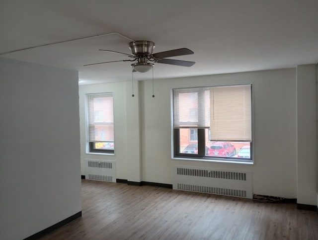 unfurnished room featuring radiator, wood-type flooring, and ceiling fan