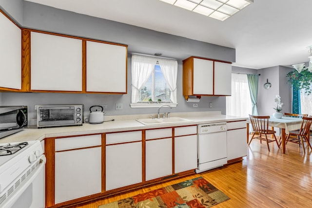 kitchen featuring white cabinetry, sink, white appliances, and plenty of natural light