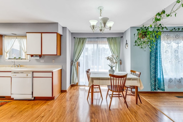 dining area featuring an inviting chandelier, sink, and light hardwood / wood-style flooring