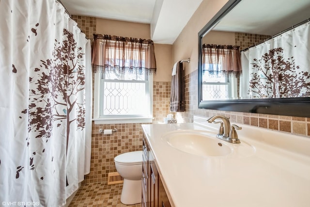 bathroom with vanity, tile walls, and toilet