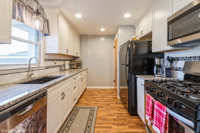 kitchen featuring sink, light hardwood / wood-style flooring, appliances with stainless steel finishes, light stone countertops, and white cabinets