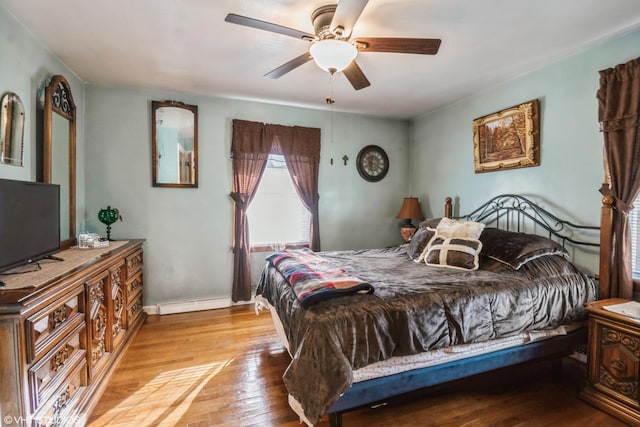 bedroom with a baseboard heating unit, ceiling fan, and light hardwood / wood-style flooring