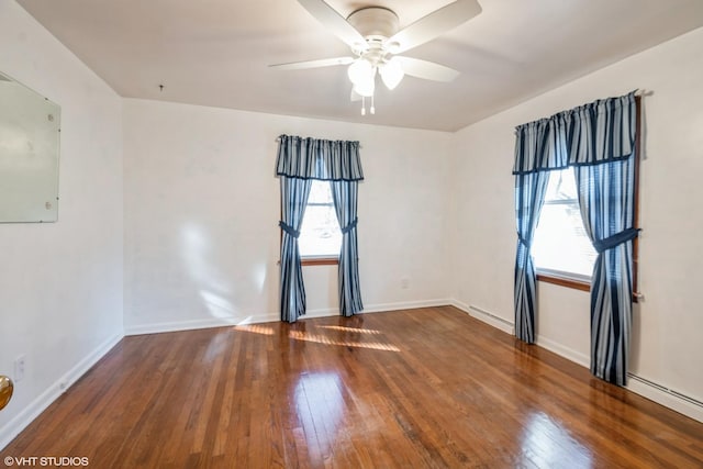 spare room with dark wood-type flooring, ceiling fan, and a baseboard heating unit