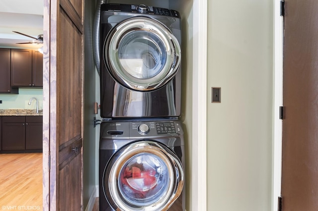 laundry room with ceiling fan, stacked washer / dryer, sink, and light hardwood / wood-style flooring