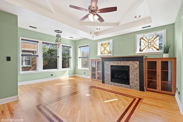 unfurnished living room with hardwood / wood-style flooring, ceiling fan, and a tray ceiling