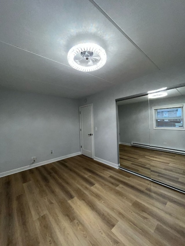 interior space with hardwood / wood-style floors, a closet, and a baseboard heating unit