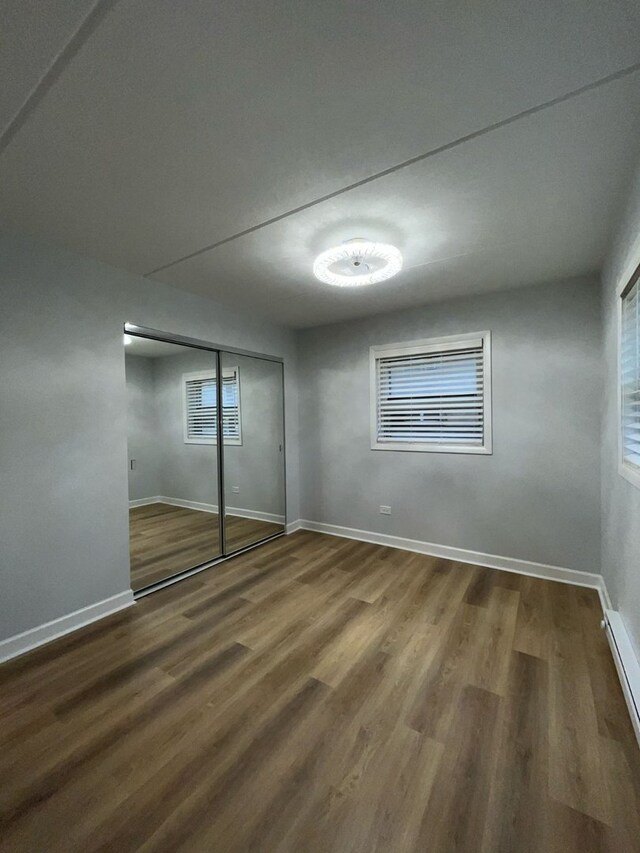 unfurnished bedroom with dark hardwood / wood-style flooring and a closet