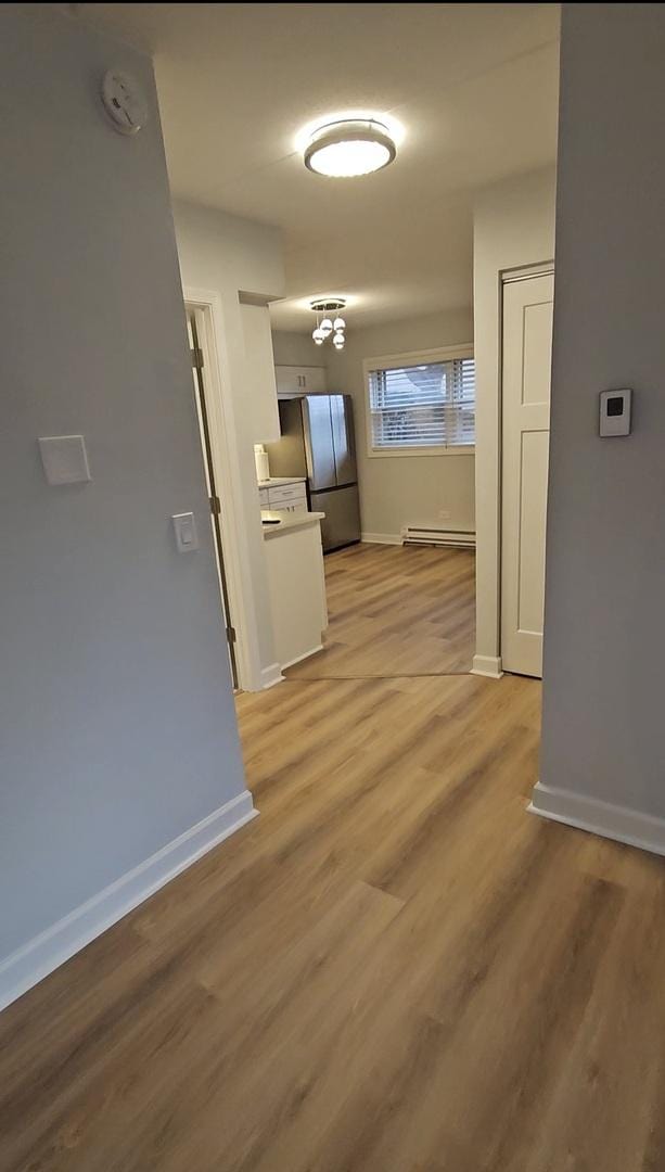 hallway featuring light wood-type flooring and baseboard heating