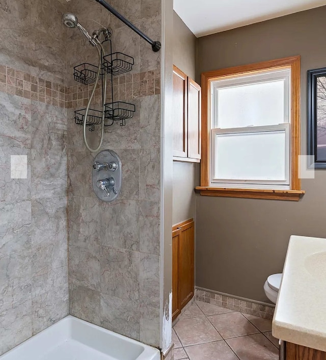 bathroom with vanity, tile patterned floors, toilet, and a tile shower