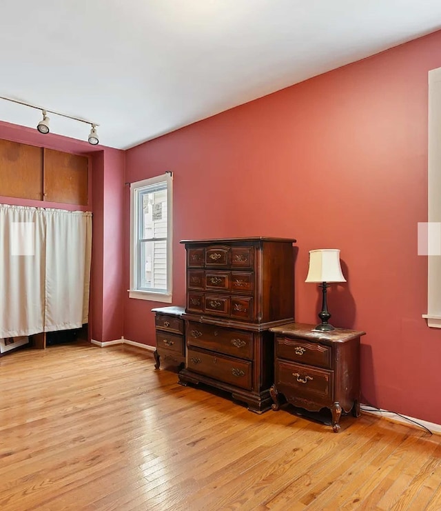 bedroom featuring rail lighting and light hardwood / wood-style flooring