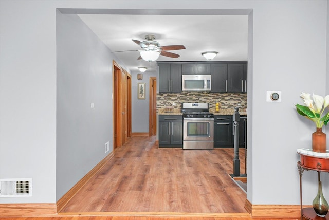 kitchen with light stone counters, light hardwood / wood-style flooring, ceiling fan, stainless steel appliances, and backsplash