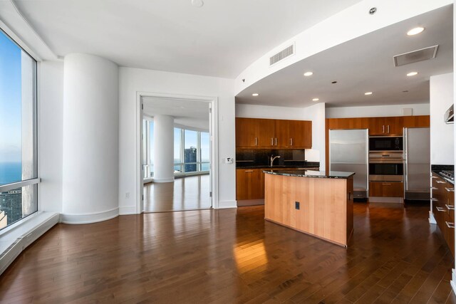 unfurnished living room featuring dark hardwood / wood-style flooring, a wealth of natural light, floor to ceiling windows, and a water view