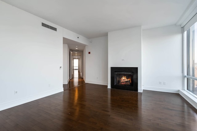 unfurnished living room featuring visible vents, a healthy amount of sunlight, and dark wood-style floors