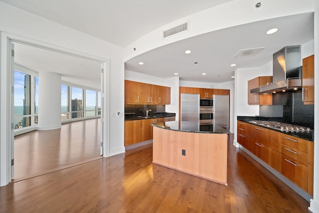 kitchen with a center island, brown cabinetry, visible vents, island range hood, and stainless steel appliances