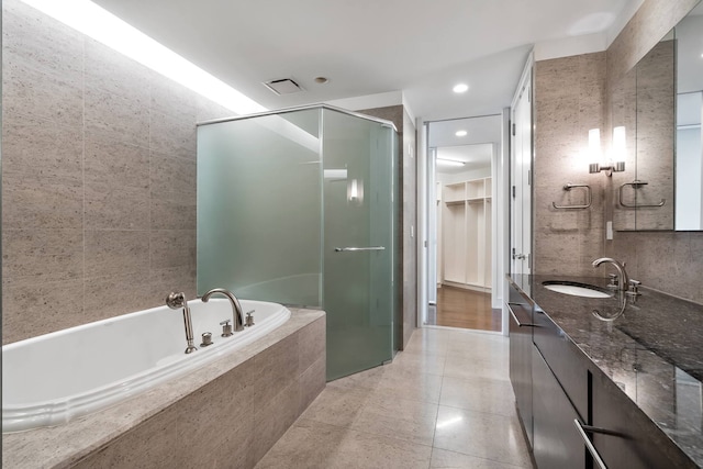 bathroom with a garden tub, a stall shower, a walk in closet, tile patterned floors, and vanity