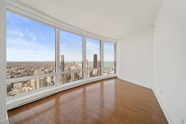 empty room with a view of city, baseboards, and hardwood / wood-style floors