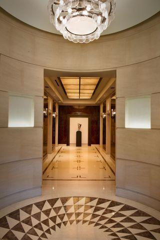 corridor featuring tile patterned floors, an inviting chandelier, and a raised ceiling
