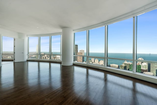 empty room featuring hardwood / wood-style flooring, a water view, a view of city, and floor to ceiling windows
