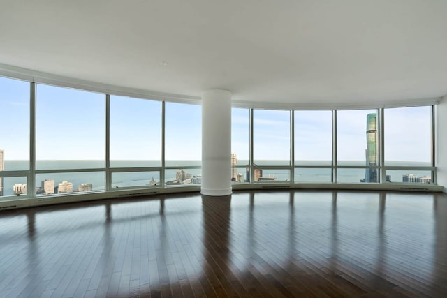 spare room featuring expansive windows, a water view, and dark hardwood / wood-style floors