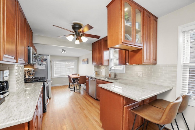 kitchen featuring light stone counters, stainless steel appliances, a kitchen breakfast bar, and sink