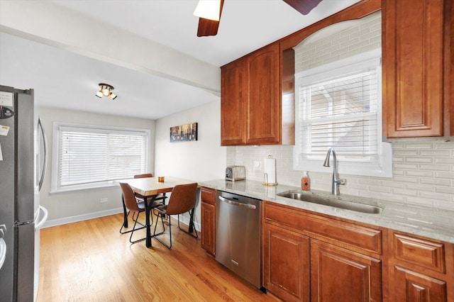 kitchen featuring stainless steel appliances, light stone countertops, sink, and light wood-type flooring