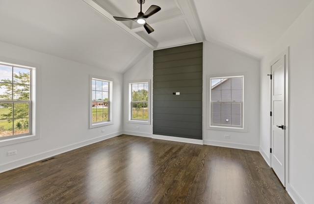 unfurnished room featuring dark hardwood / wood-style floors, vaulted ceiling with beams, and ceiling fan