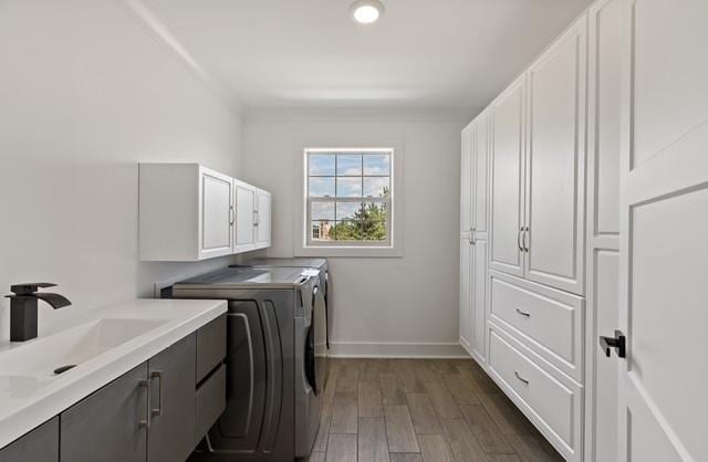 clothes washing area with sink, crown molding, cabinets, dark hardwood / wood-style floors, and independent washer and dryer