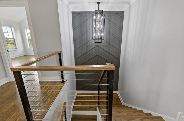 stairs featuring wood-type flooring and a chandelier