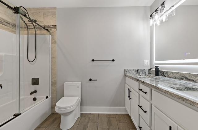 full bathroom with bath / shower combo with glass door, vanity, and toilet