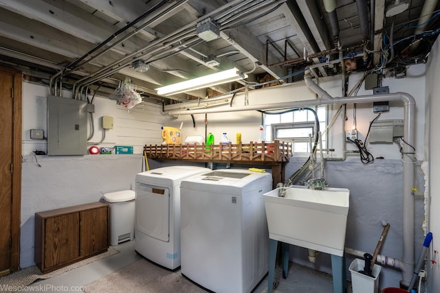 washroom with sink, washing machine and dryer, and electric panel