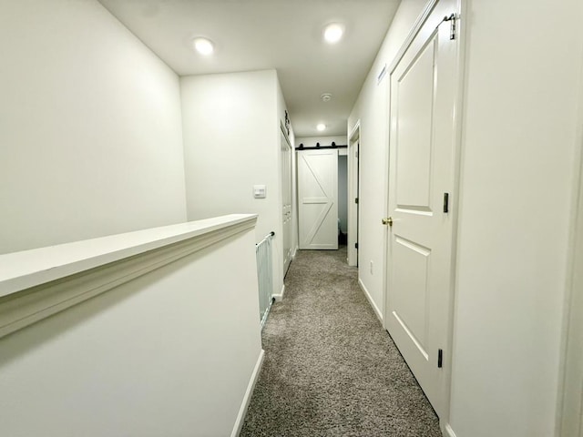 hall featuring a barn door and carpet flooring