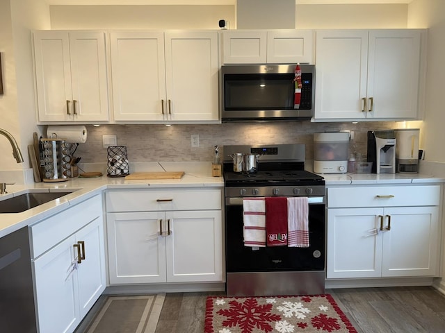 kitchen with dark wood-type flooring, sink, stainless steel appliances, decorative backsplash, and white cabinets